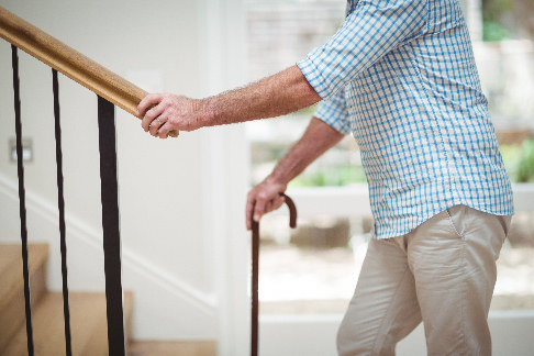 Älterer Mann, der nach Operation, die Treppe hochgeht.